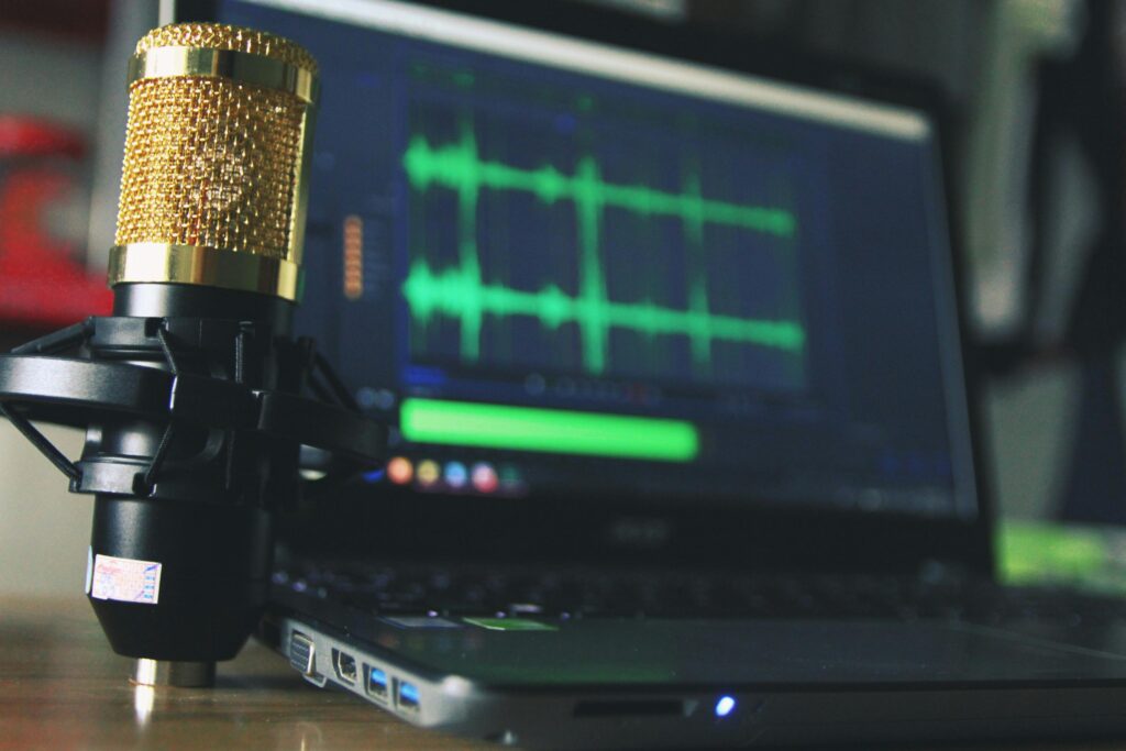 Close-up of a golden microphone and laptop used for audio editing.